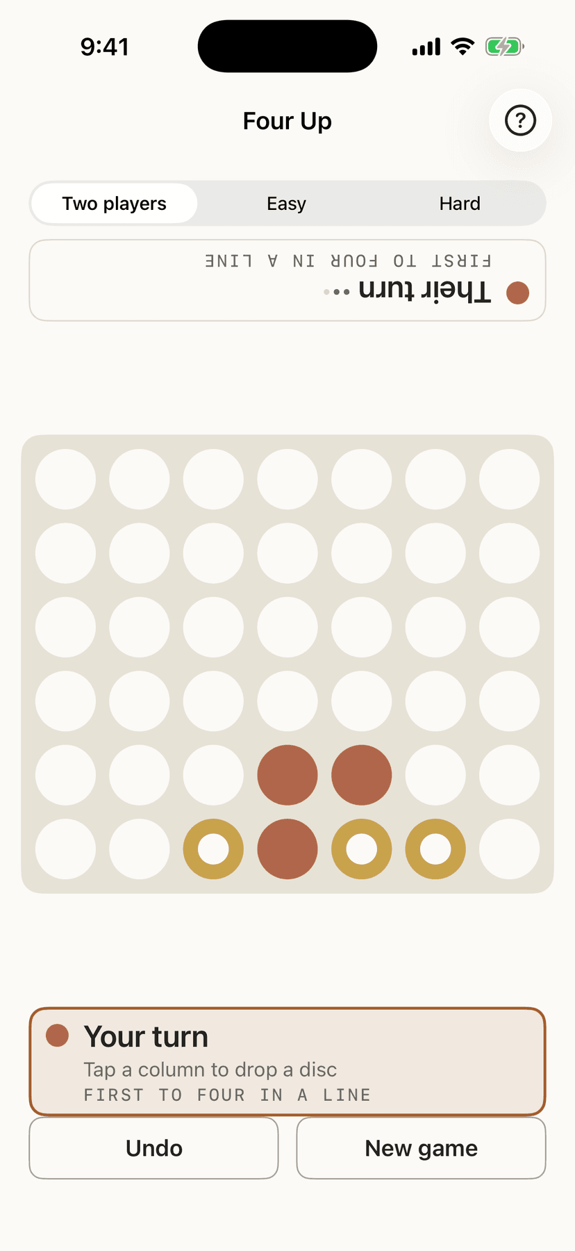 Four Up part-way through a game between two people: one side's discs are solid, the other's are rings, and whose turn it is appears at both ends of the screen, one way up each.